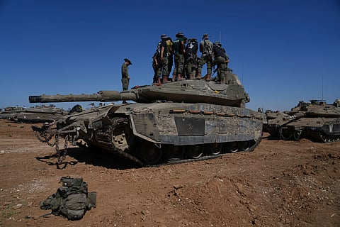 Israeli soldiers work on armored military vehicles at a staging ground near the Israeli-Gaza border, in southern Israel, Wednesday, May 8, 2024. 