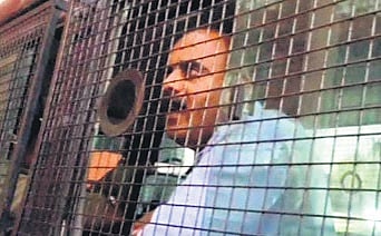 Devaraje Gowda talks to the media from a police van in Hassan on Friday