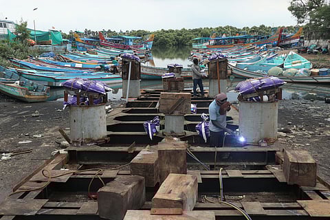 Shipyard worker performing arc welding; two individuals working aboard a ship in Puducherry Port
