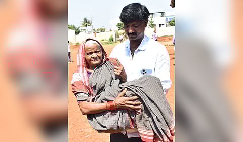 A man carries Lakshmavva, 80, after she cast her vote in Adargunchi village in Dharwad district on Tuesday