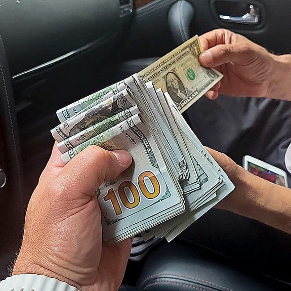 In this June 2023 photo taken by an undercover agent and provided by the U.S. Attorney's office, an undercover agent posing as a hitman, left, holds money received as a partial advance payment for murder during a transaction in New York. U.S. officials became aware in the spring of a plot to kill Gurpatwant Singh Pannun.