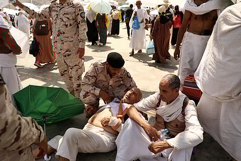 A man affected by the scorching heat is helped by a member of the Saudi security forces as pilgrims arrive to perform the symbolic 'stoning of the devil' ritual as part of the Hajj pilgrimage in Mina, near Mecca