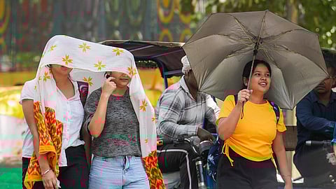 Women take cover under a scarf on a hot summer day amid heatwave.
