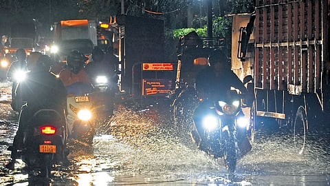 Motorists carefully glide past an inundated road at Bazaar Street, during a heavy downpur in Bengaluru on Sunday.