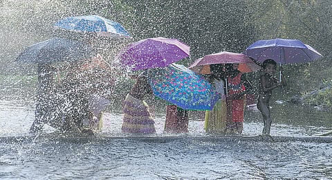 Tribal children playing in the rain holding Karthumbi umbrellas 