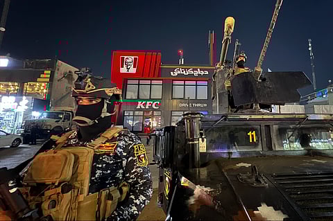 Iraqi security forces stand guard in front of Kentucky Fried Chicken restaurant in Baghdad, Wednesday, June 5, 2024. 