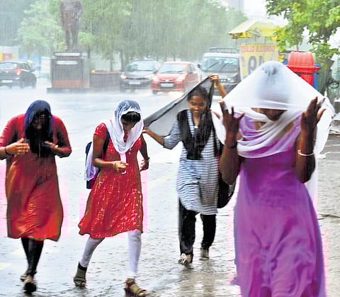 Women cover themselves using stoles as rains lash Karimnagar on Sunday