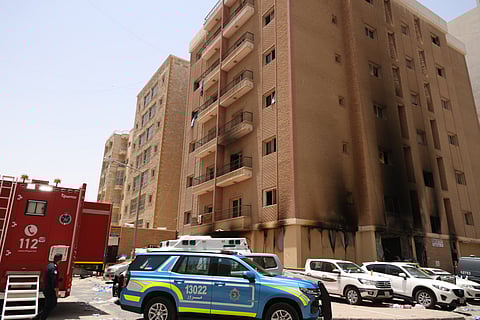 Kuwaiti firefighters and security forces gather outside a building which was ingulfed by fire, in Kuwait City, on June 12, 2024.