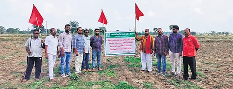 District Cooperative Bank officials hoist red flags on agricultural land owned by farmer Banda Rajasekhar Reddy in Polkampet village at Kamareddy on Friday