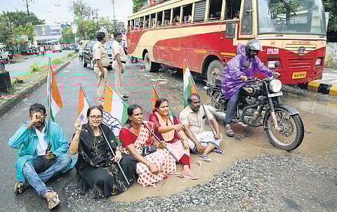 Congress workers stage a sit-in on the pothole-ridden Kaloor-Kadavanthra road on Monday