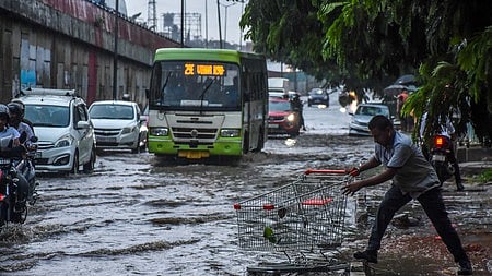 A man retrieving a shopping cart which has swept away in rain water from a shopping mall into the flooded NH16 service road as heavy rain laesh Bhubaneswar on Tuesday.