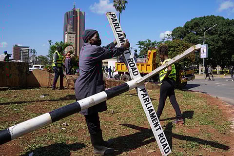 Protesters hide behind a banner as police fire tear gas at them during a protest over proposed tax hikes in a finance bill in downtown Nairobi, Kenya Tuesday.