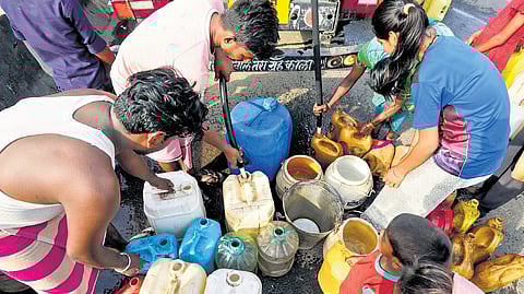 People collect drinking water from a Delhi Jal Board tanker in Geeta Colony area on Sunday.