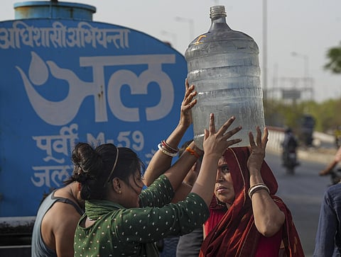 File Photo | A woman carries drinking water collected from a tanker of Delhi Jal Board on a hot summer day