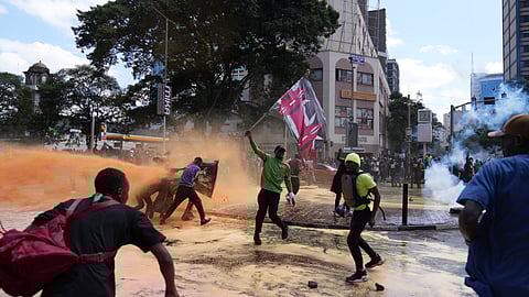 Protesters scatter as Kenya police spray a water canon at them during a protest over proposed tax hikes in a finance bill in downtown Nairobi, Kenya Tuesday.