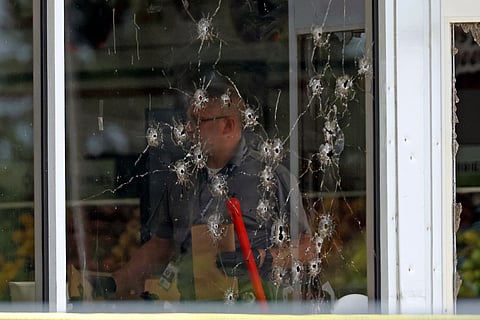 Damage can be seen to a front window law enforcement officers work the scene of a shooting at the Mad Butcher grocery store in Fordyce