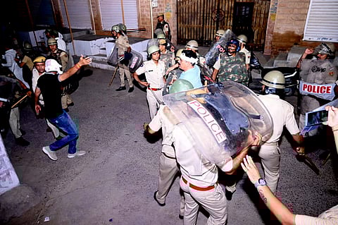 Police personnel detain a person after stone pelting took place during a clash between two groups, in Jodhpur, Friday night, June 21, 2024.