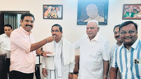 MP Pralhad Joshi meets BJP leader B S Yediyurappa and fellow MP BY Raghavendra before being sworn-in as minister, in New Delhi on Sunday.