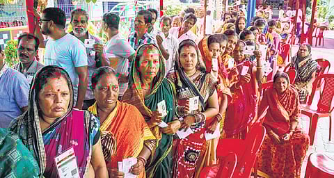 People show their identity cards while waiting in queues to cast their votes at a polling booth in Jagatsinghpur, on Saturday