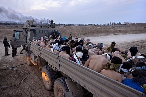 Israeli soldiers stand by a truck packed with bound and blindfolded Palestinian detainees, in Gaza on Dec. 8, 2023. 