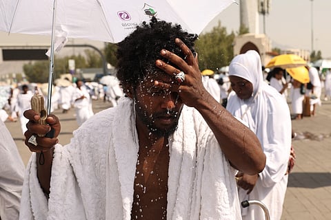 A Muslim pilgrim splashes water on his head to cools off at the base of Saudi Arabia's Mount Arafat, also known as Jabal al-Rahma or Mount of Mercy, during the climax of the Hajj pilgrimage on June 15, 2024