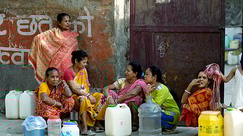 People wait for a water tankers arrival to collect drinking water as the national capital faces a water crisis, at New Ashok Nagar area in New Delhi, Wednesday, June 12, 2024. 