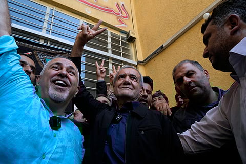 Reformist candidate for the Iran's presidential election Masoud Pezeshkian, center, flashes a victory sign after casting his vote as he is accompanied by former Foreign Minister Mohammad Javad Zarif, left, at a polling station in Shahr-e-Qods near Tehran, Iran, Friday, July 5, 2024.