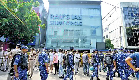 Security personnel stand guard near the coaching centre where three civil services aspirants drowned.
