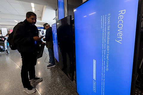A Delta technician works on a set of screens displaying a blue page and reading “Recovery” in Terminal 2, Delta Airlines, at Los Angeles airport, on July 19, 2024.