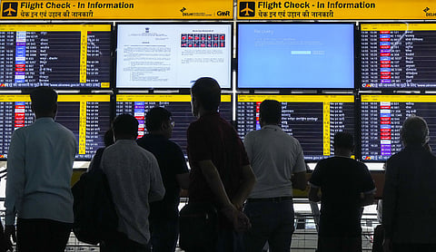 Passengers look at screens, one of them showing Blue Screen error, at T3 Terminal of the Indira Gandhi International Airport