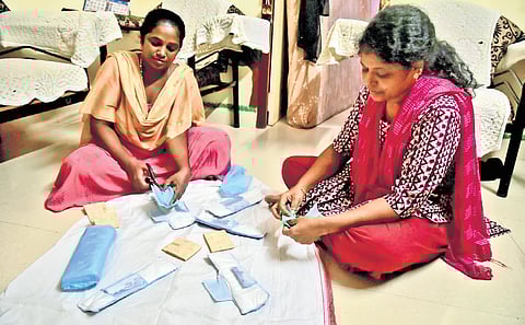 women are making organic napkins using handmade machines.