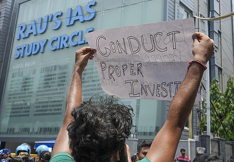 A student holds a poster during a protest outside Rau's IAS Study Circle where three students died after the basement of the building flooded due to the rains in Delhi.