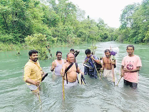 Health staffers, led by Mulugu DMHO Dr A Appaiah, cross a waterbody to conduct a medical camp in Penugodium village under Wazeedu mandal in Mulugu district