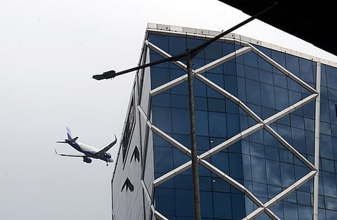 An airplane fying low over office building with plate glass walls in Chennai.