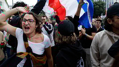 People wave French flags as they react to projected results after the second round of the legislative elections, Sunday, July 7.