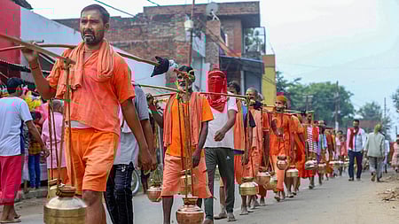 Kanwariyas walk past a shop on which banners with shopkeeper's name was put up after an order issued by the Uttar Pradesh government 