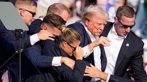 Republican presidential candidate former President Donald Trump is helped off the stage by U.S. Secret Service agents at a campaign event in Butler, Pa., on Saturday, July 13, 2024.