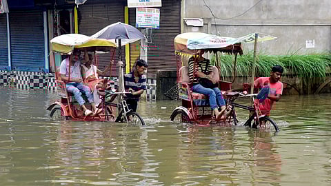Rickshaw pullers wade through Assam floods
