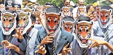 Students wear tiger masks to mark International Tiger Day to create awareness on saving the animals in Bengaluru on Monday.