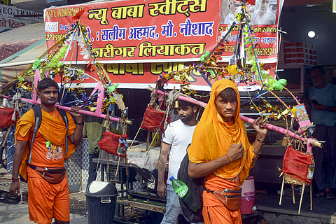 Kanwariyas walk past a shop on which banners with shopkeeper's name was put up after an order issued by the Uttar Pradesh government 