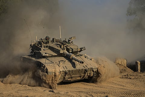 An Israeli soldier moves on the top of a tank near the Israeli-Gaza border, as seen from southern Israel, Sunday, July 14, 2024.