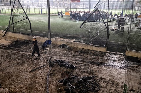  A boy walks past bicycles left next to a soccer pitch that was hit by a rocket, killing 12 children and teenagers, in the Druze town