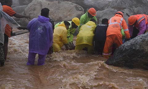 A group of rescue volunteers and officials work to recover a body from the landslide site.