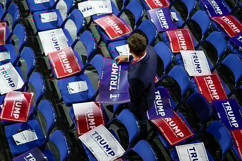 A worker puts out Trump signs during the Republican National Convention Monday, July 15, 2024, in Milwaukee.