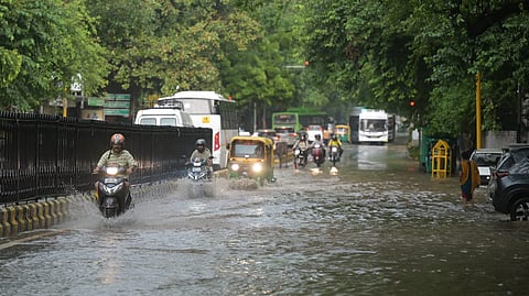 Commuters wade through a waterlogged road after rains, in New Delhi on Friday.