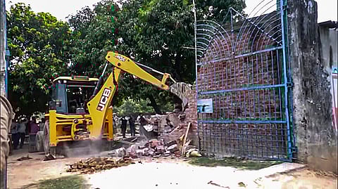 An excavator being used to demolish an illegal shopping complex owned by Moin Khan, an accused in a gang-rape case, in Ayodhya.