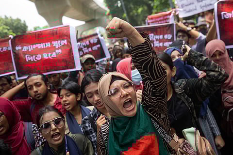 A policeman aims his weapon at protesters during a curfew imposed following violence during protests against Prime Minister Sheikh Hasina and her government, in Dhaka