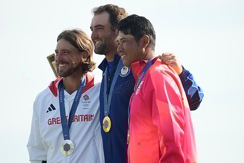 Gold medalist Scottie Scheffler, of the United States, centre, with Tommy Fleetwood, of Britain, silver medal, and Hideki Matsuyama, of Japan, with the bronze medal pose for the media following the medal ceremony for men's golf at the 2024 Summer Olympics