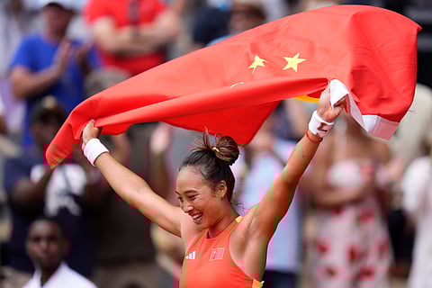 China's Zheng Qinwen holds a Chinese flag after defeating Croatia's Donna Vekic during the Women's Singles tennis final at the Roland Garros stadium at the 2024 Summer Olympics.