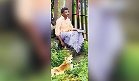 Praveen Kumar, who lost his brother in the landslide, sits outside the relief camp with his pet dog at Meppadi 